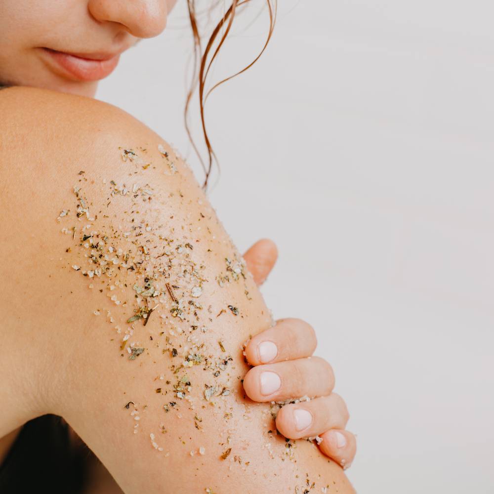 Mulher jovem a aplicar esfoliante corporal no braço